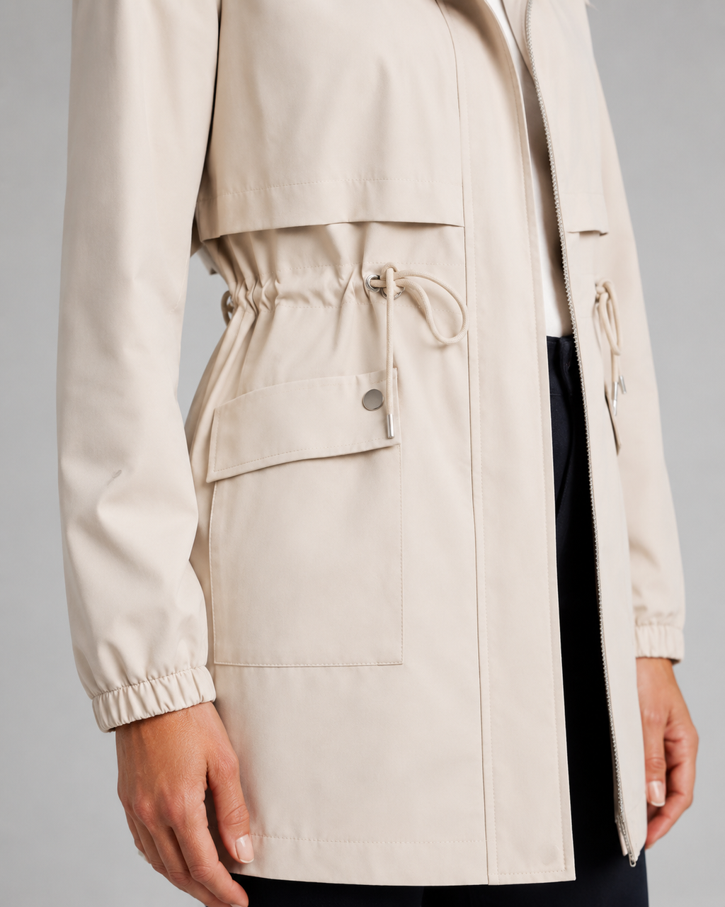 Beige women's trench coat with drawstring hooded waist detail, cropped fit, and large cargo pockets