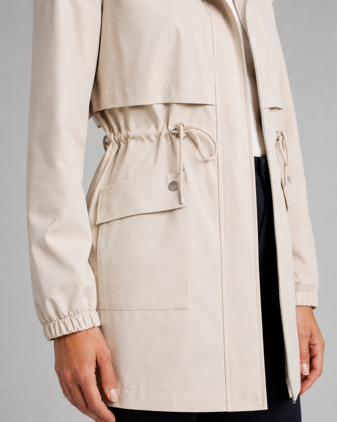 Beige women's trench coat with drawstring hooded waist detail, cropped fit, and large cargo pockets
