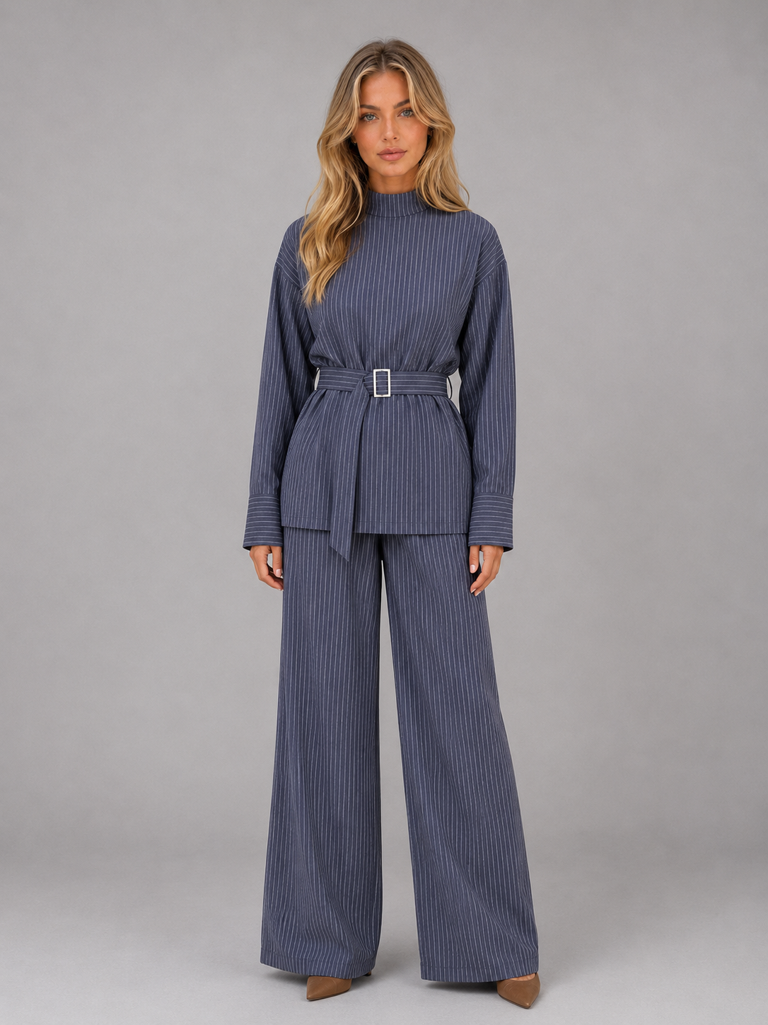 Woman wearing navy pinstripe high neck long sleeve top with belt and matching wide leg trousers two-piece set, styled with brown shoes