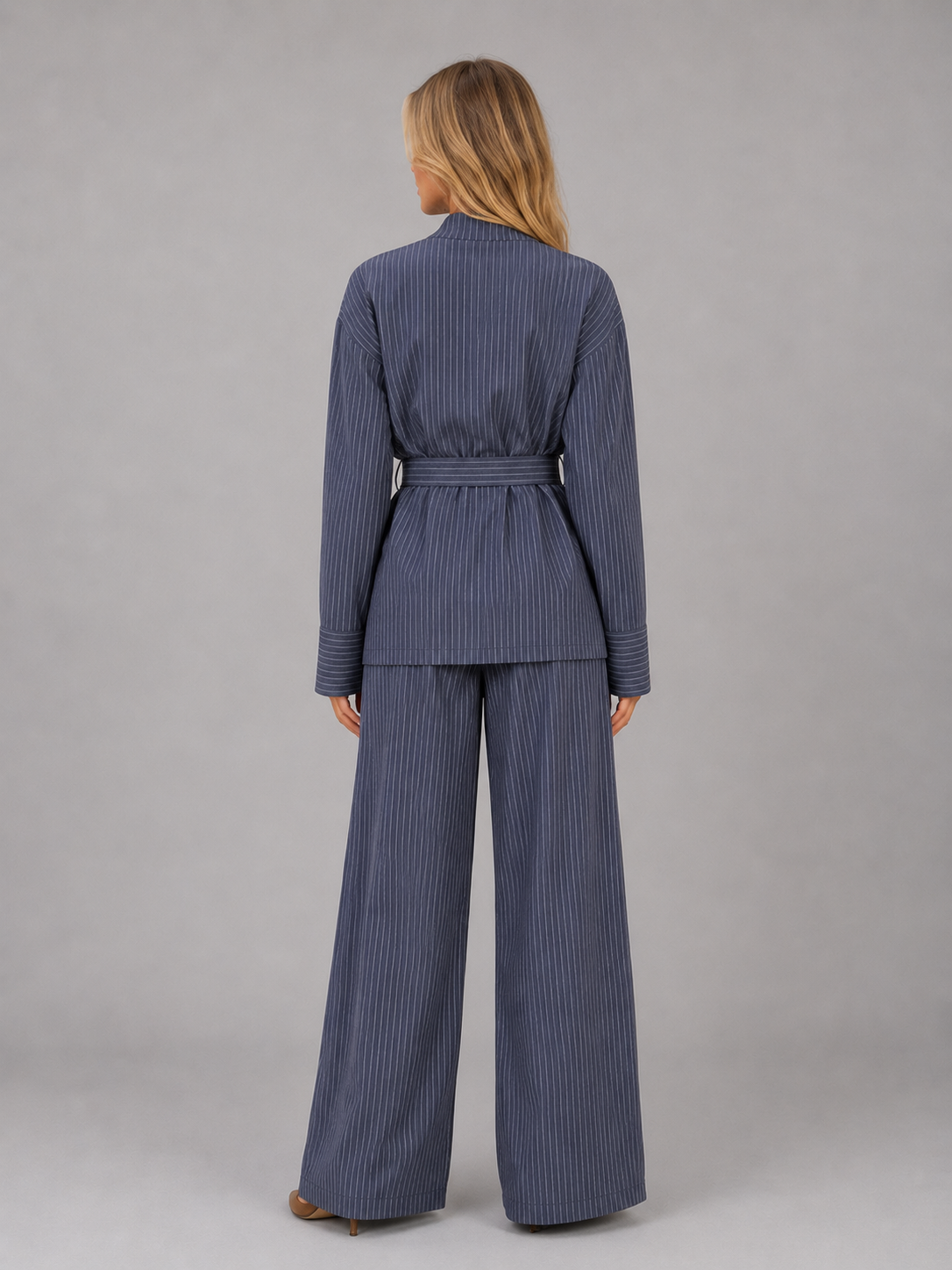 Woman wearing navy blue pinstripe high neck top with belt and matching wide leg trousers two-piece set, back view