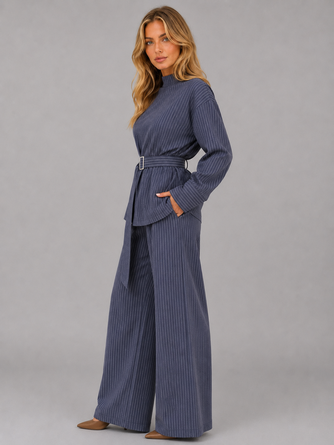 Woman wearing navy pinstripe high neck long sleeve top with belt and matching wide leg trousers two-piece set