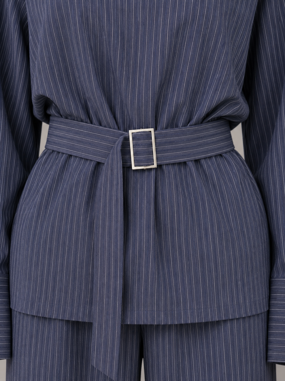 Navy pinstripe two-piece set with high neck top, wide leg trousers, and matching belt with silver buckle