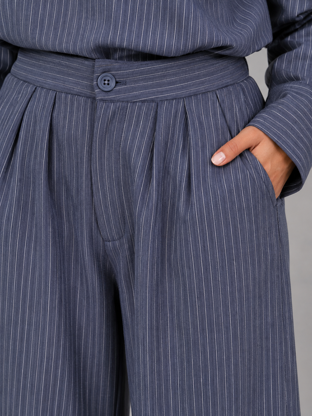 Woman wearing navy pinstripe high neck top and wide leg trousers two-piece set with hand in pocket