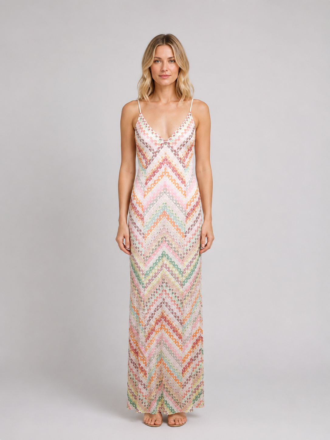 Woman wearing colorful boho crochet knit maxi dress with chevron pattern in pastel pink, orange, green and cream colors