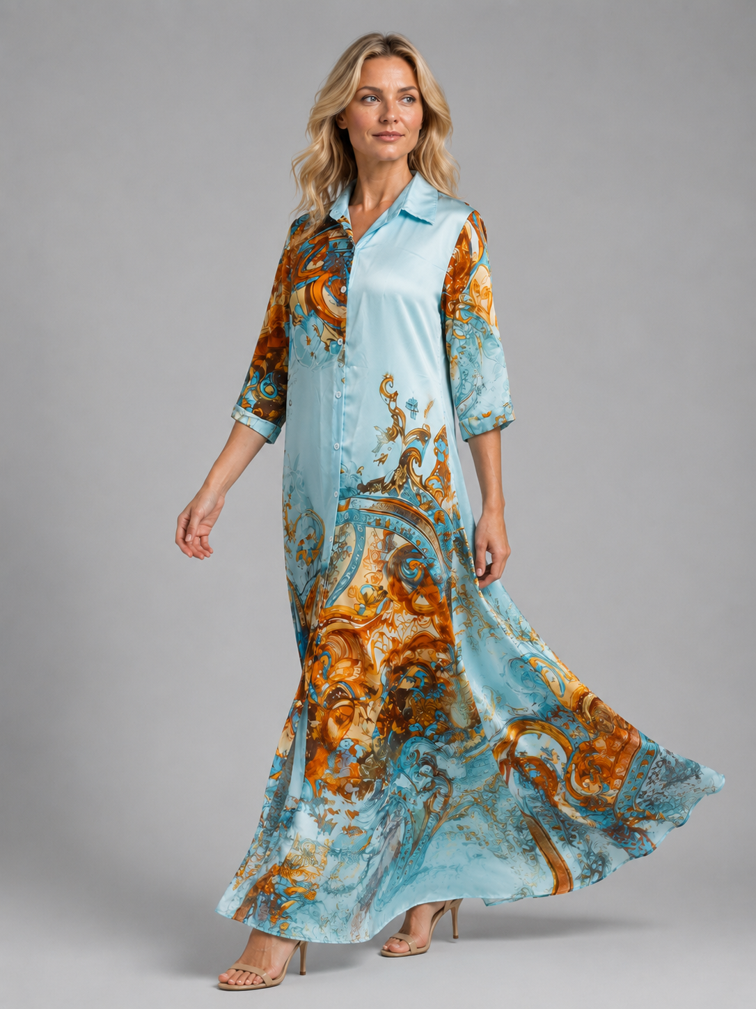 Woman wearing light blue button-front maxi dress with orange and teal baroque print pattern, three-quarter sleeves, paired with beige sandals