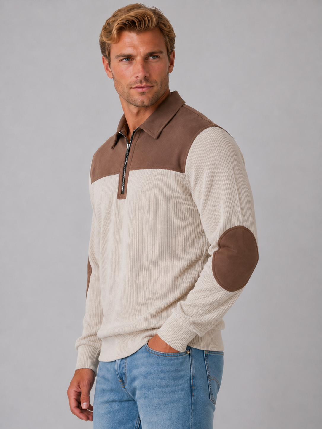 Man wearing cream ribbed long sleeve pullover with brown quarter zip, elbow patches, and collar, styled with blue jeans