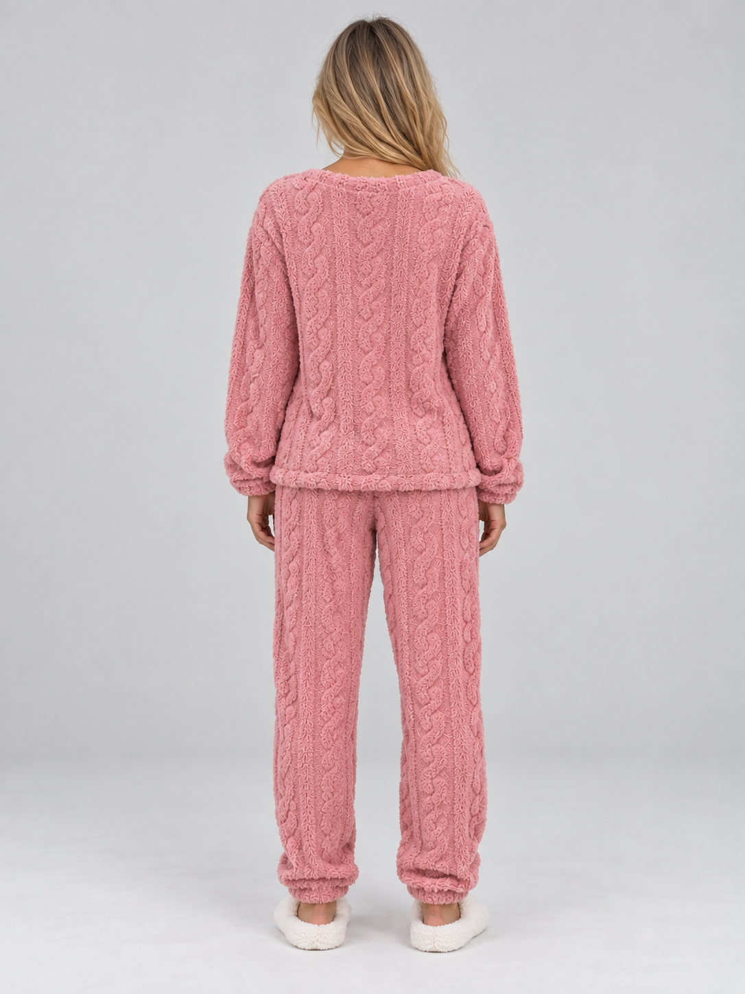 Woman wearing pink cable knit thermal fleece pajama set with long sleeves and matching trousers, shown from back view