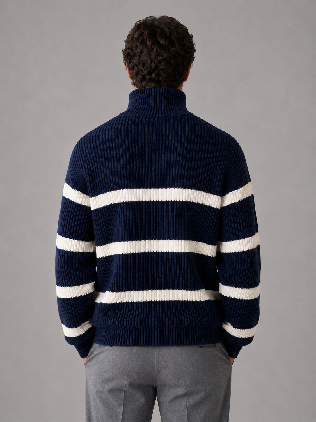 Man wearing navy and white striped ribbed turtleneck pullover with half zip, back view, styled with gray trousers