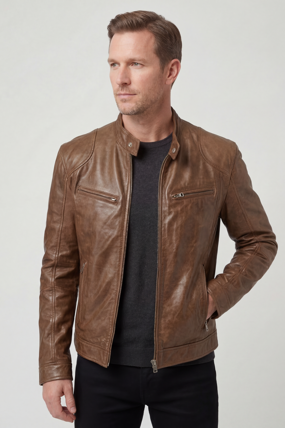 Man wearing brown leather jacket with zip pockets over black t-shirt, standing against white background