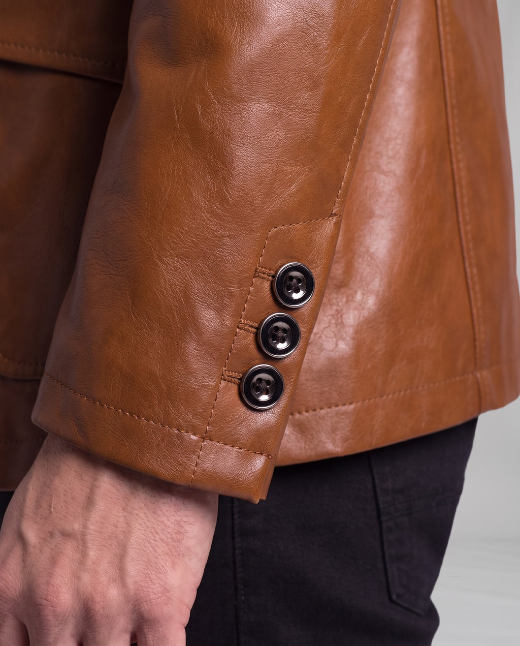 Close-up of the Soren leather blazer sleeve cuff in Cognac Brown with three metal-rimmed buttons