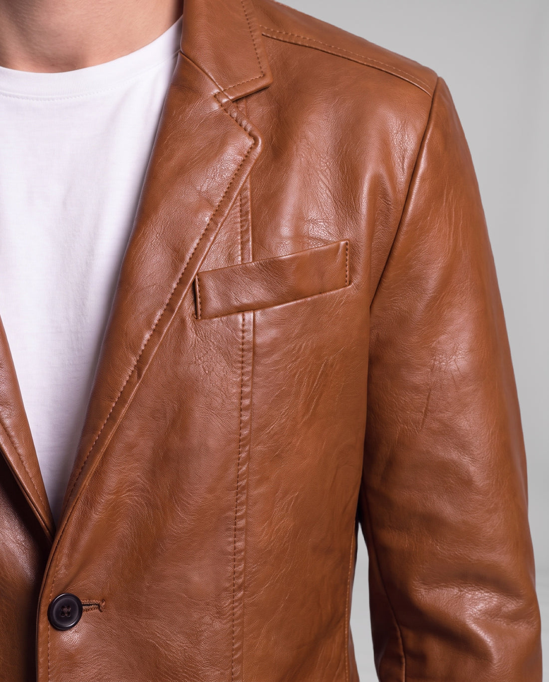 Close-up of the Soren leather blazer in Cognac Brown: notch lapel, welt chest pocket, topstitching and leather grain