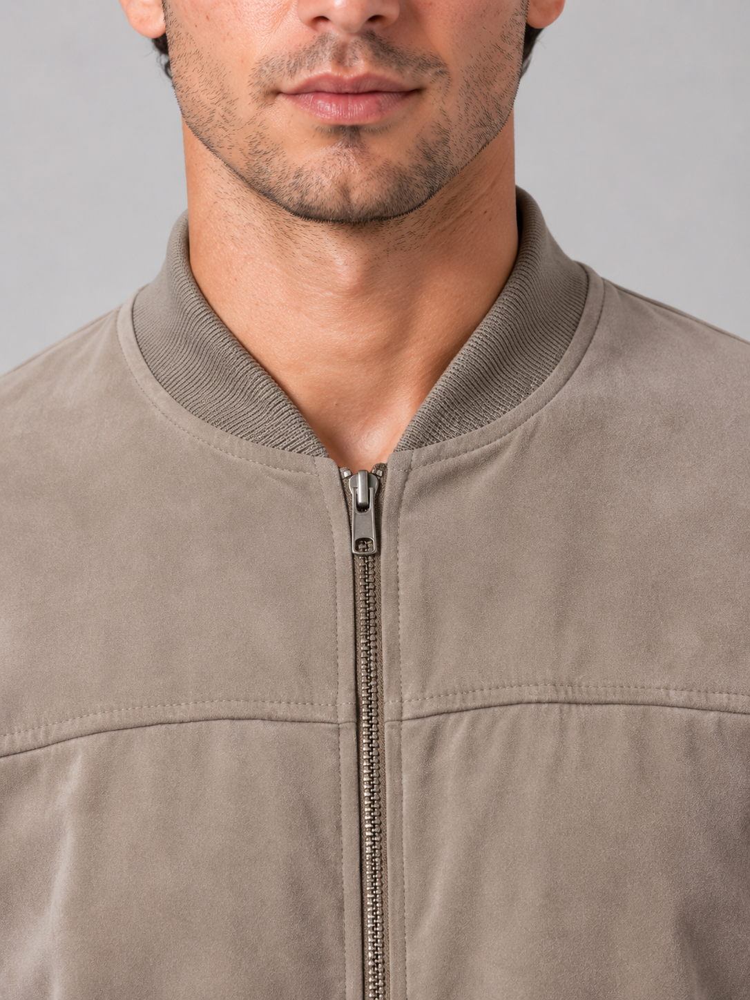 Man wearing beige regular fit zip bomber jacket with ribbed collar and chest pocket detail against gray background