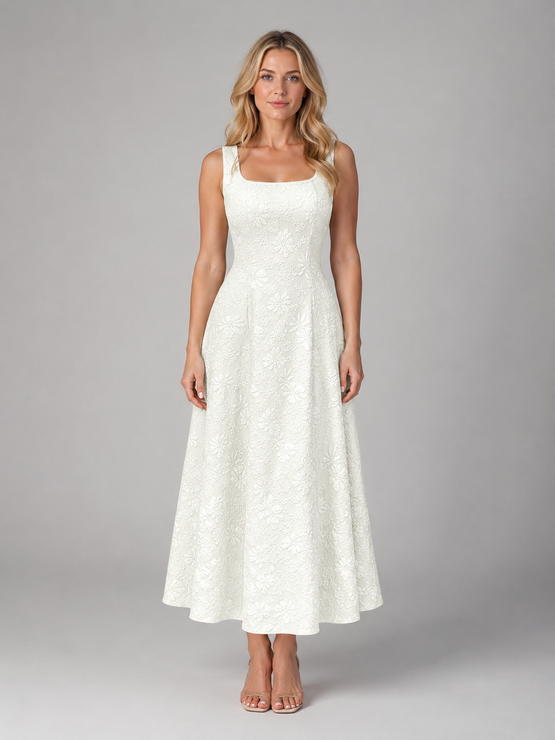 Woman wearing white floral jacquard sleeveless midi dress with square neckline and full skirt, paired with tan sandals