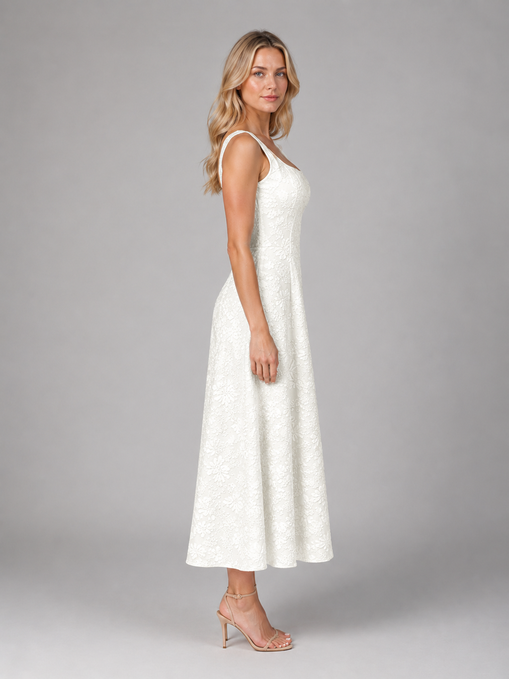 Woman wearing white floral jacquard sleeveless midi dress with A-line silhouette and nude heeled sandals