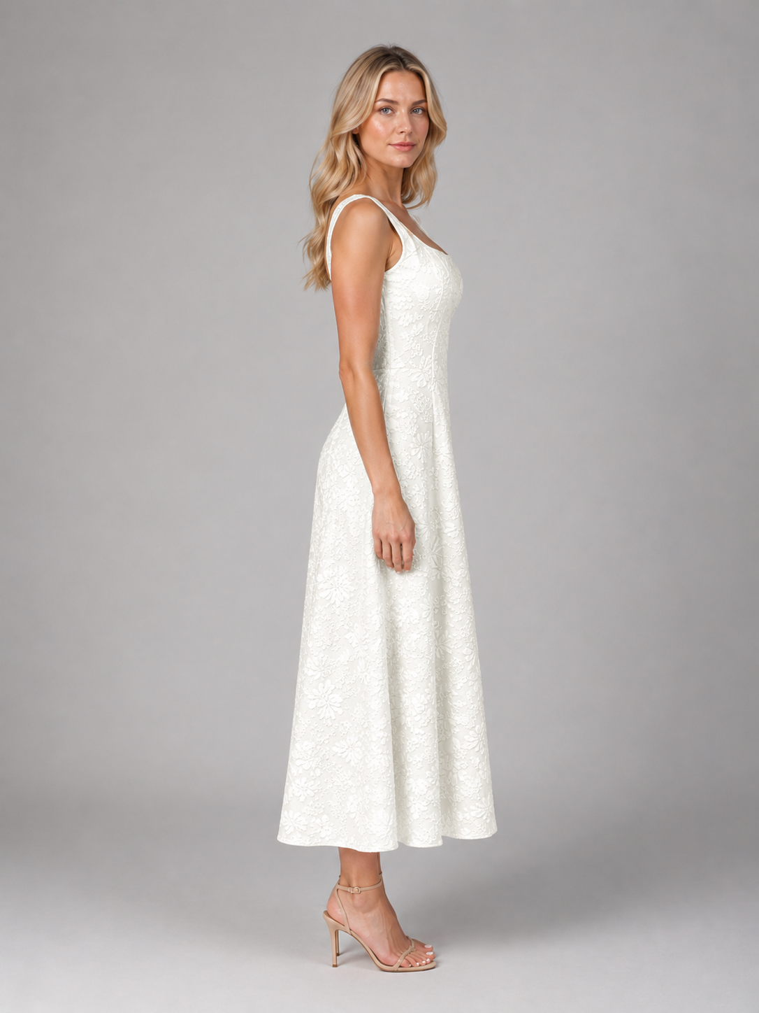 Woman wearing white floral jacquard sleeveless midi dress with A-line silhouette and nude heeled sandals