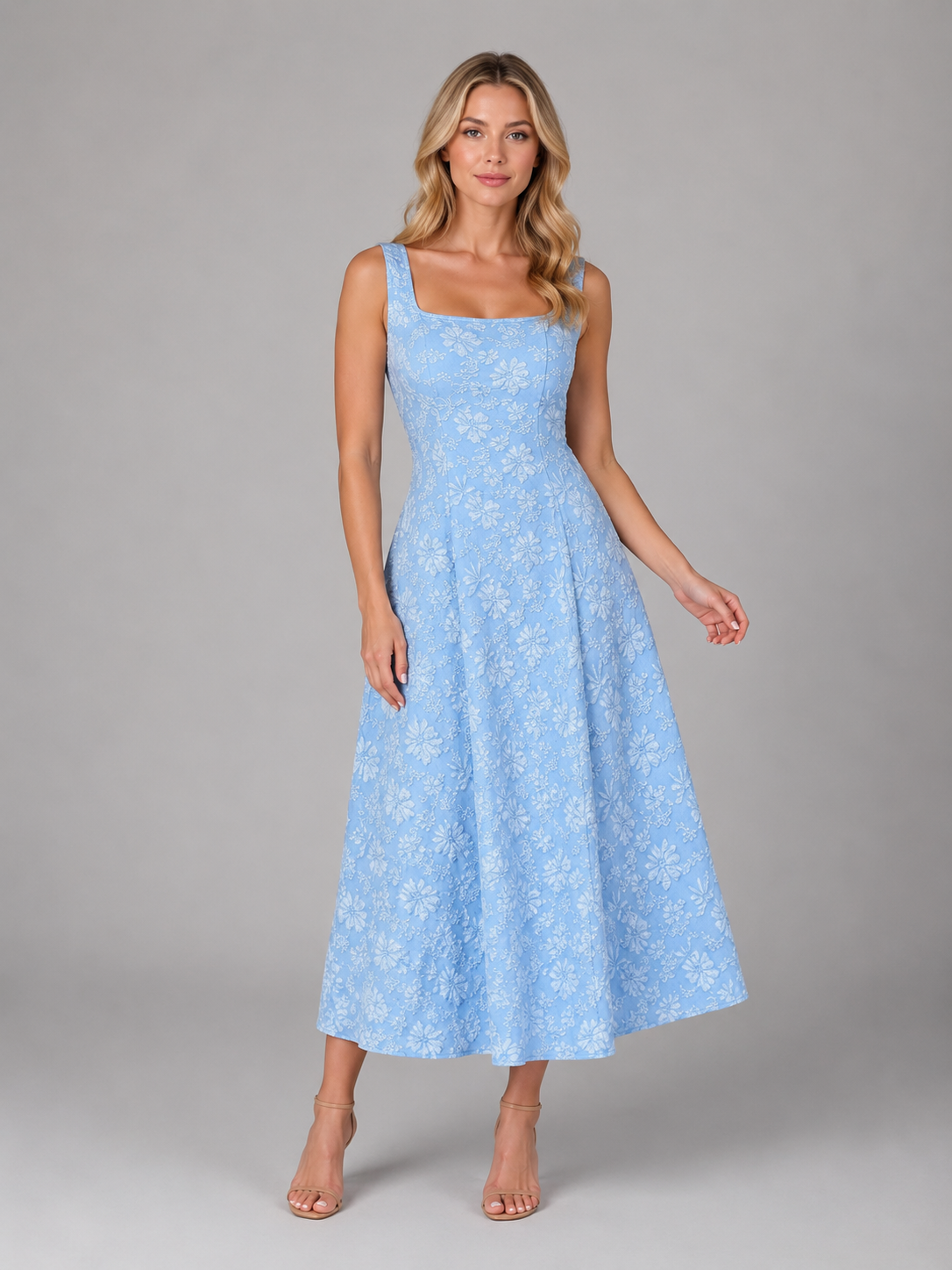 Woman wearing a light blue floral jacquard sleeveless midi dress with a square neckline, standing against a gray background