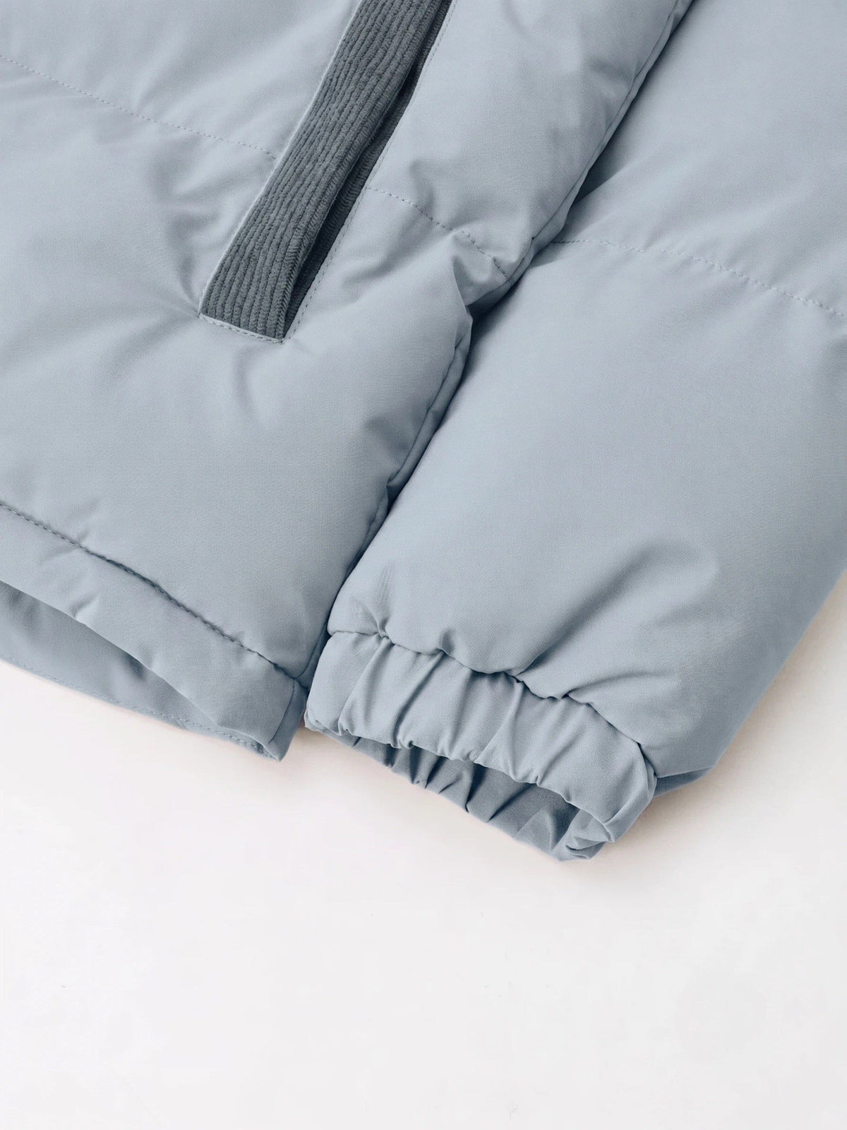 Light gray padded puffer jacket with ribbed collar detail and elastic cuffs, showing quilted seams and puffy construction