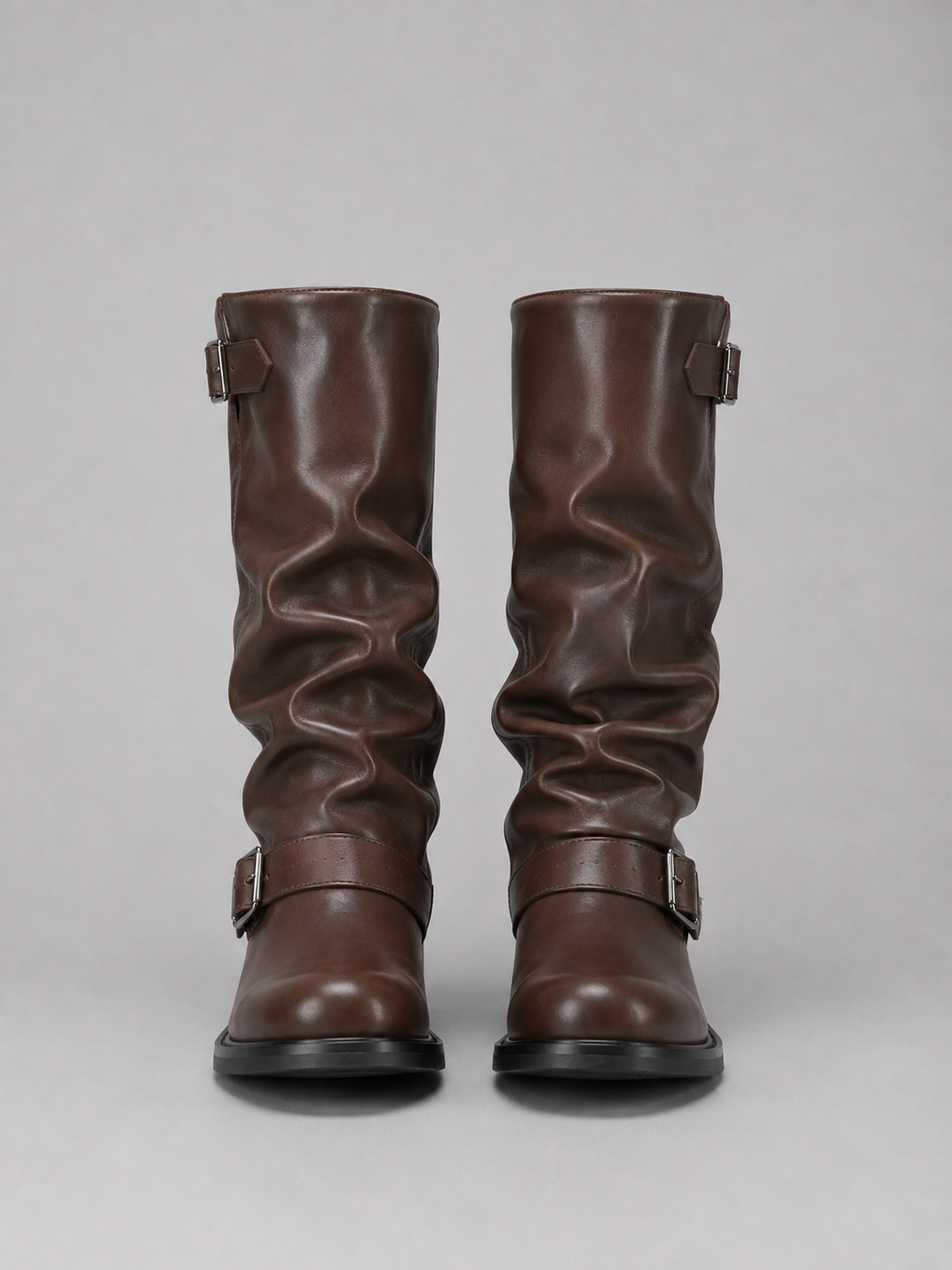 Brown leather knee-high biker boots with buckle straps and gathered shaft detail, front view on gray background