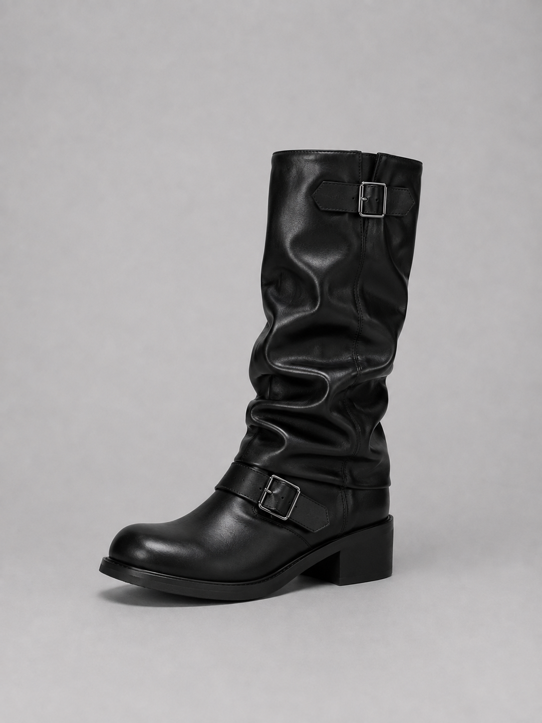 Black leather knee-high biker boots with buckle straps and low block heel on gray background