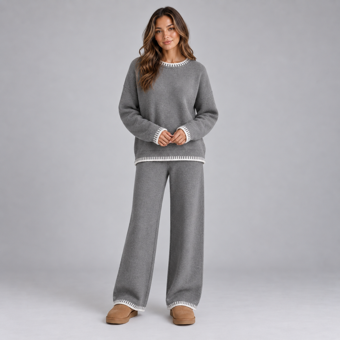 Woman wearing gray knit lounge set with white contrast trim on crew neckline, cuffs, and pant legs, styled with tan slippers