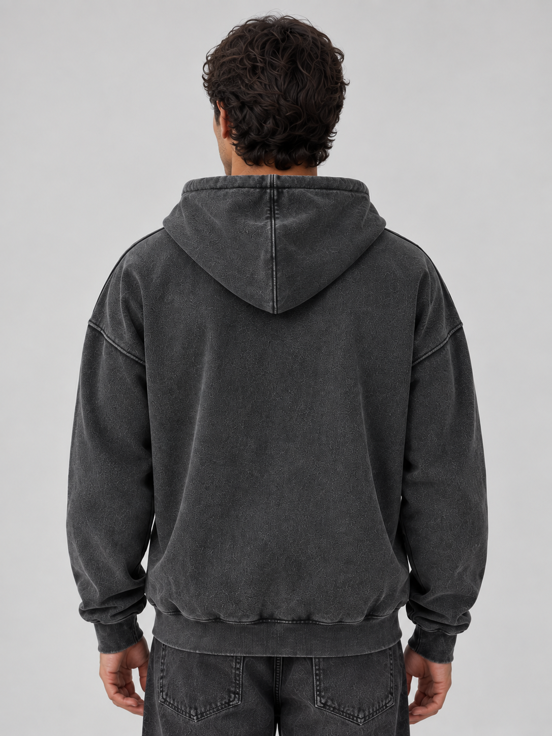 Man wearing charcoal washed full zip oversized hooded jacket with ribbed cuffs and hem, shown from back view
