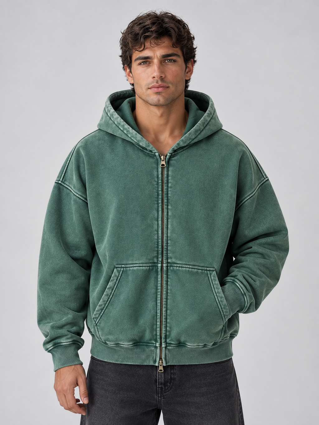 Man wearing green washed oversized full zip hoodie with kangaroo pocket over dark jeans, front view