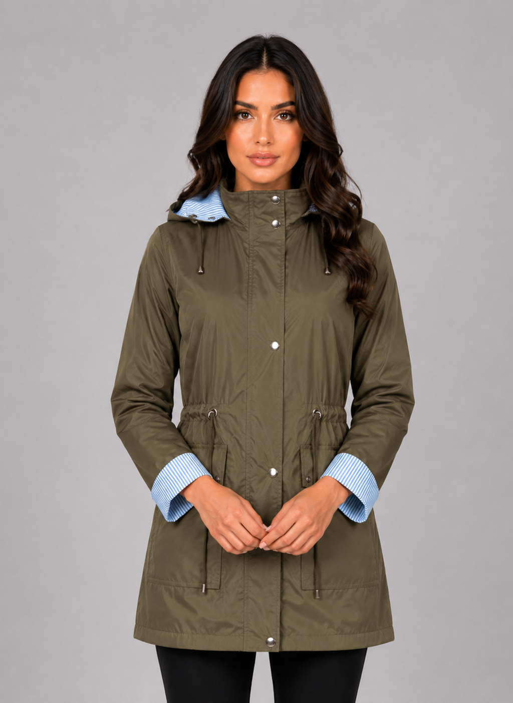 Woman wearing olive green lightweight water resistant hooded rain jacket with blue striped cuffs and drawstring waist