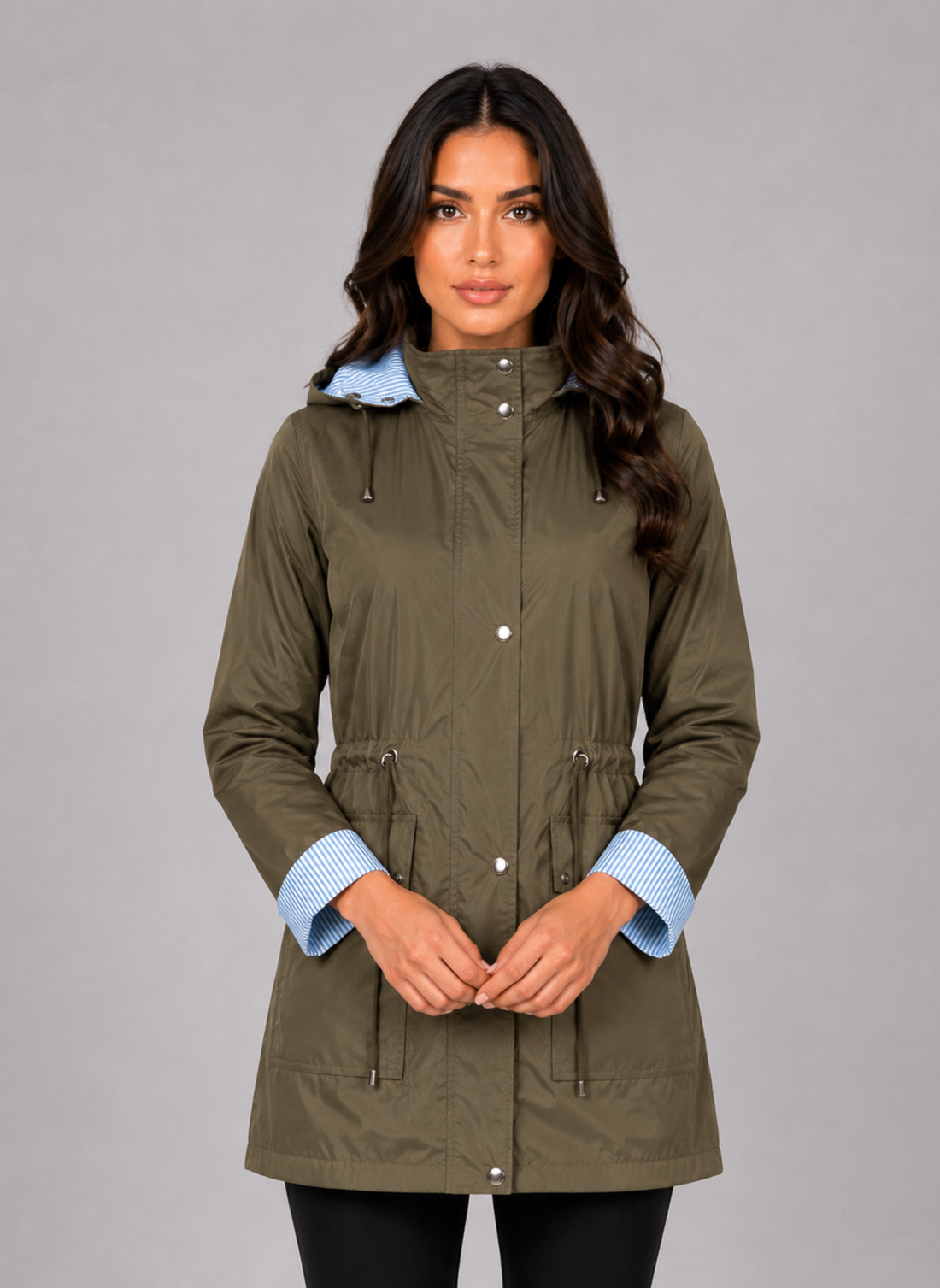 Woman wearing olive green lightweight water resistant hooded rain jacket with blue striped cuffs and drawstring waist