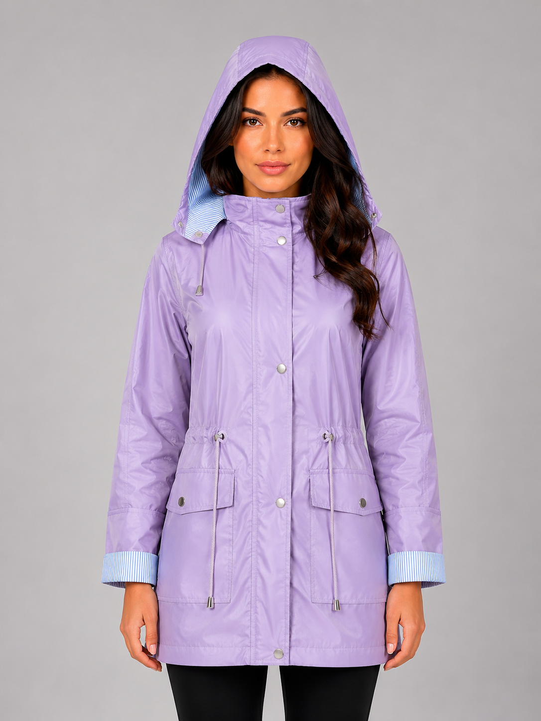 Woman wearing lavender lightweight water resistant hooded rain jacket with blue striped trim and front pockets
