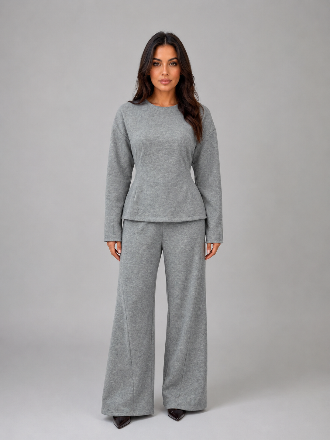 Woman wearing gray long-sleeve fitted top and matching wide-leg lounge pants on white background