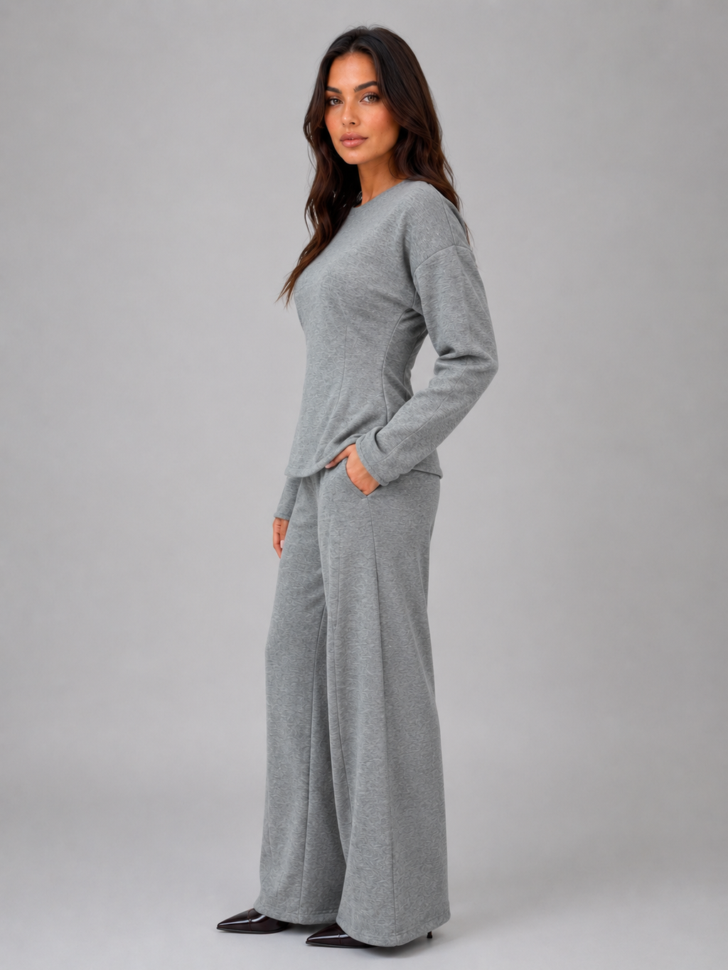 Woman wearing gray fitted long-sleeve top and matching wide-leg lounge pants with orange elbow patches and hand pockets