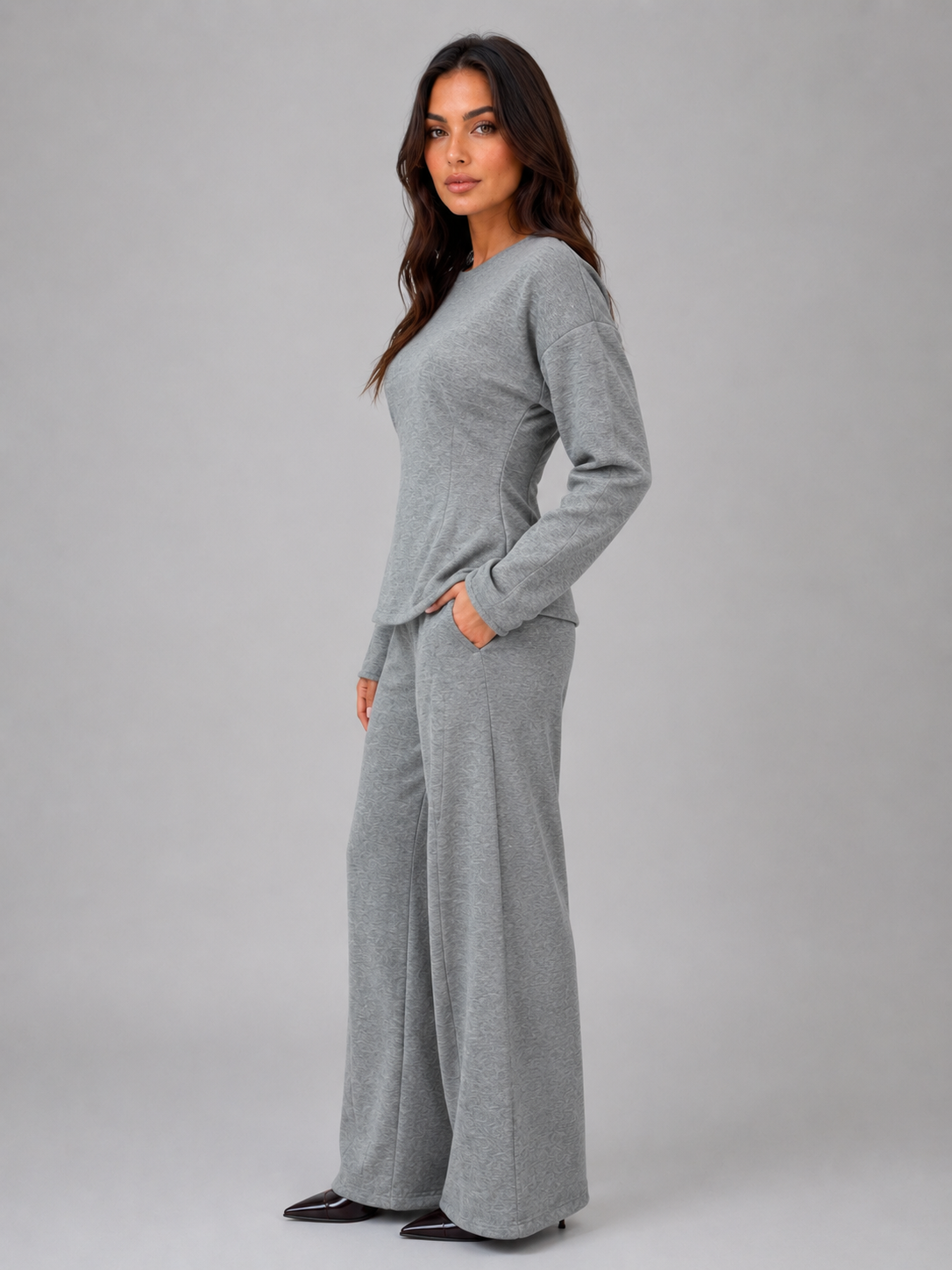 Woman wearing gray fitted long-sleeve top and matching wide-leg lounge pants with orange elbow patches and hand pockets