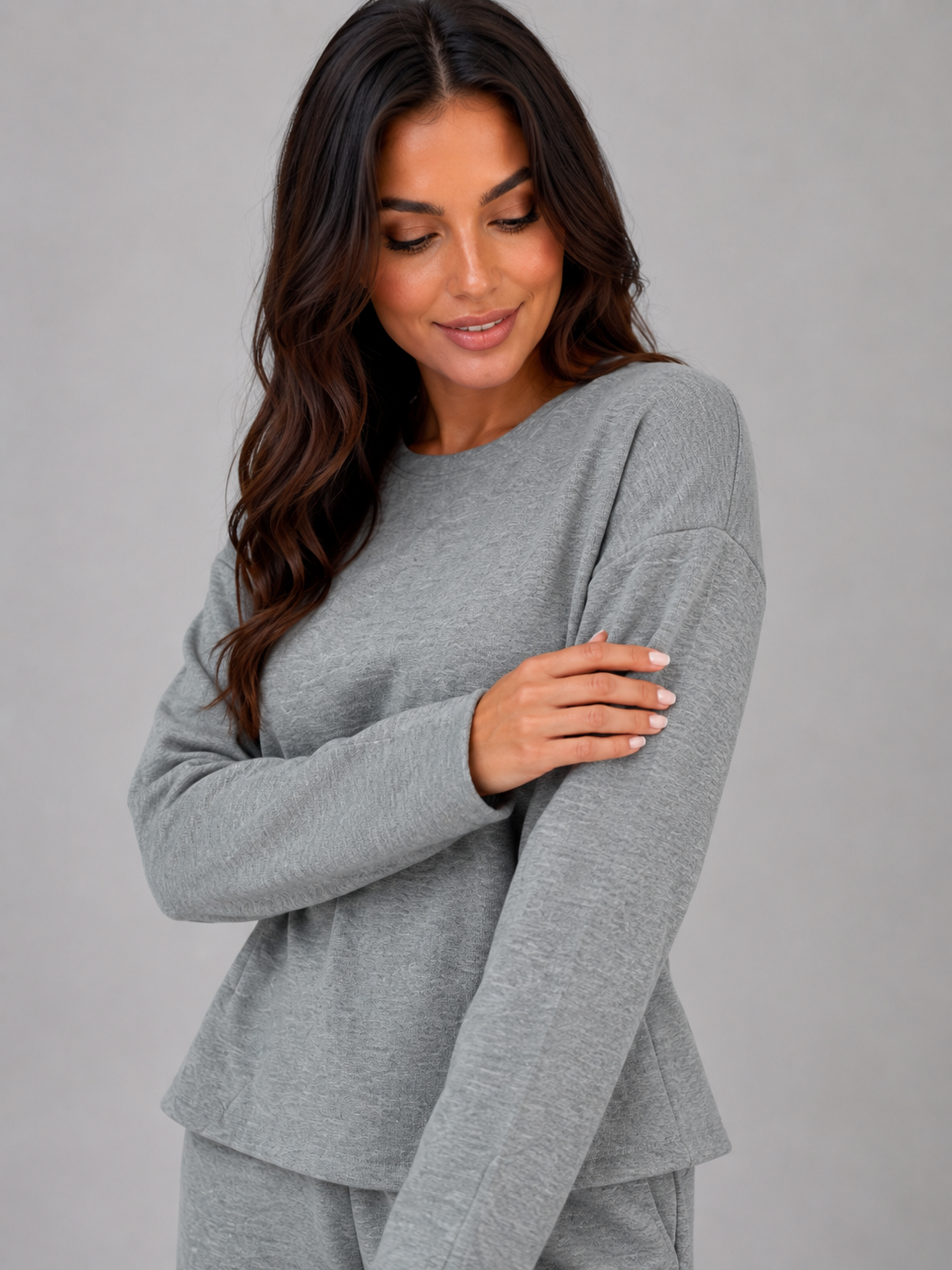 Woman wearing gray fitted long-sleeve top and wide-leg lounge pants set, looking down with arms crossed