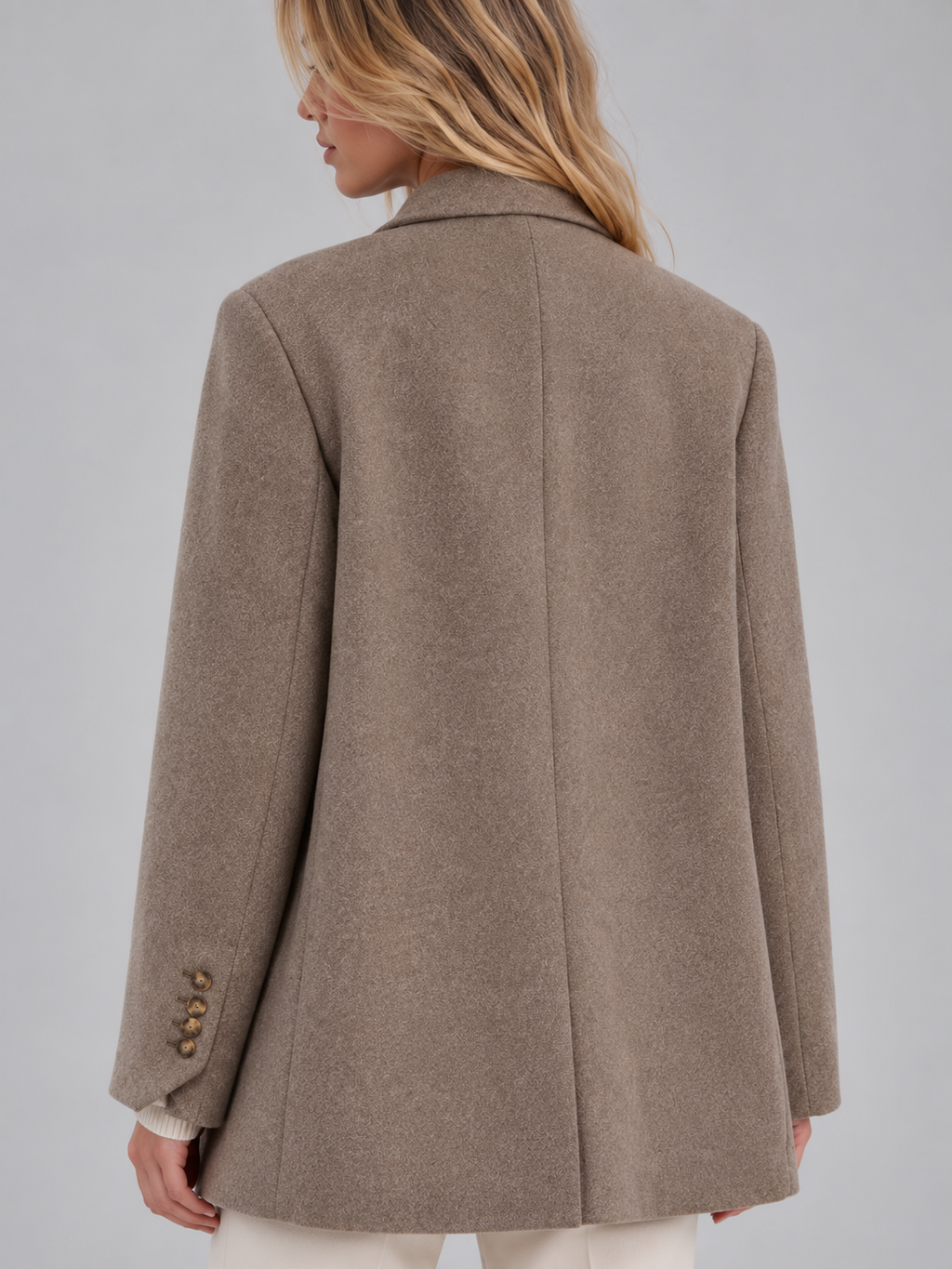 Woman wearing a taupe tailored longline double-breasted oversized blazer with button cuffs, shown from back