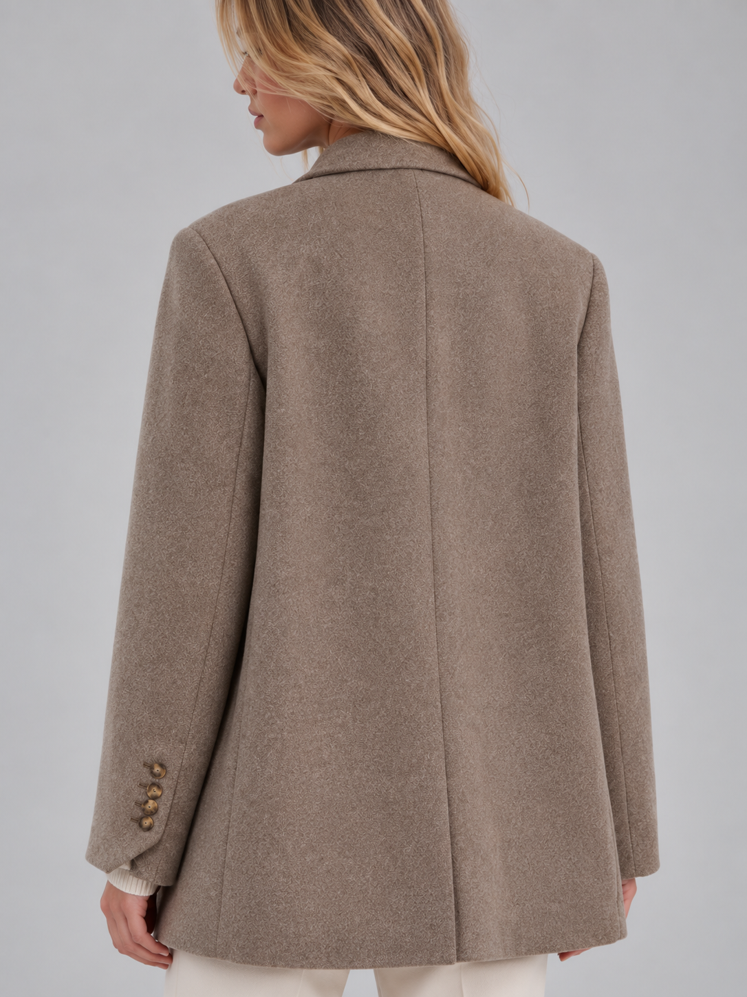 Woman wearing a taupe tailored longline double-breasted oversized blazer with button cuffs, shown from back