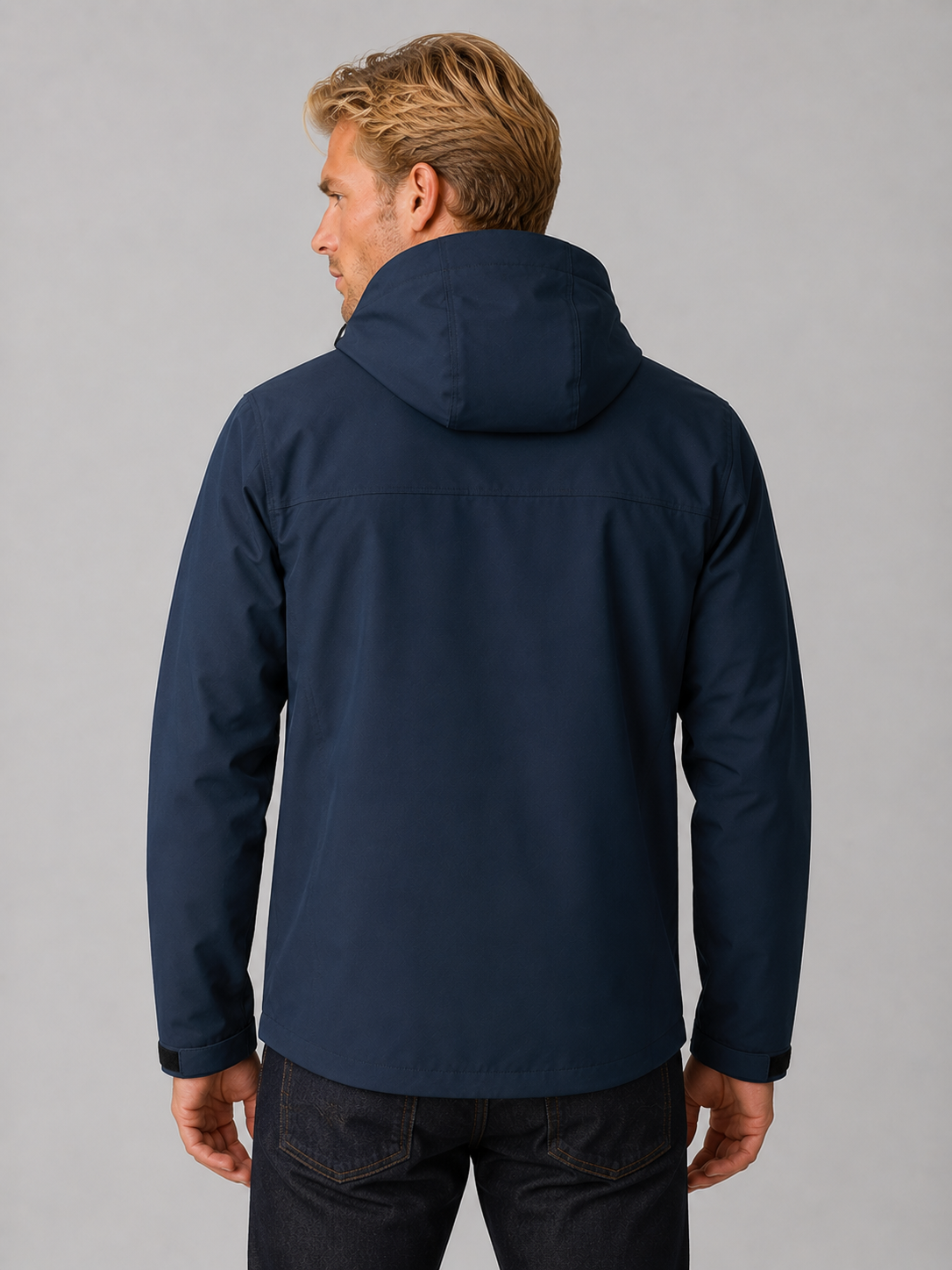 Man wearing navy blue hooded zip-up windbreaker jacket viewed from behind, showing water-resistant fabric and adjustable cuffs