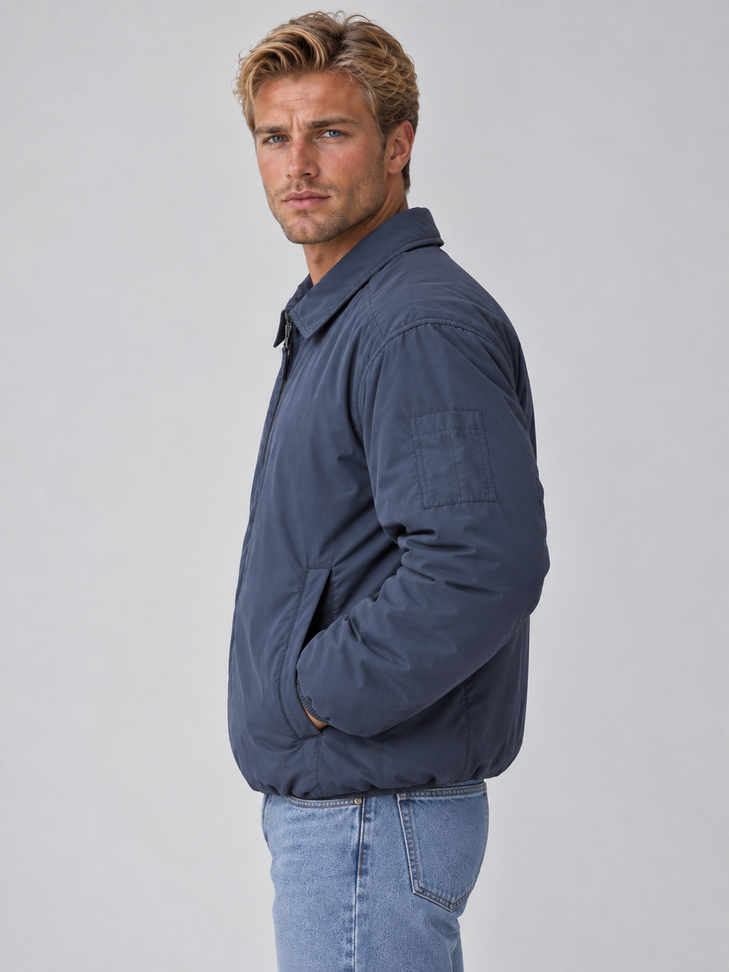 Man wearing navy lightweight padded collared bomber jacket with full zip and chest pocket, styled with light blue jeans
