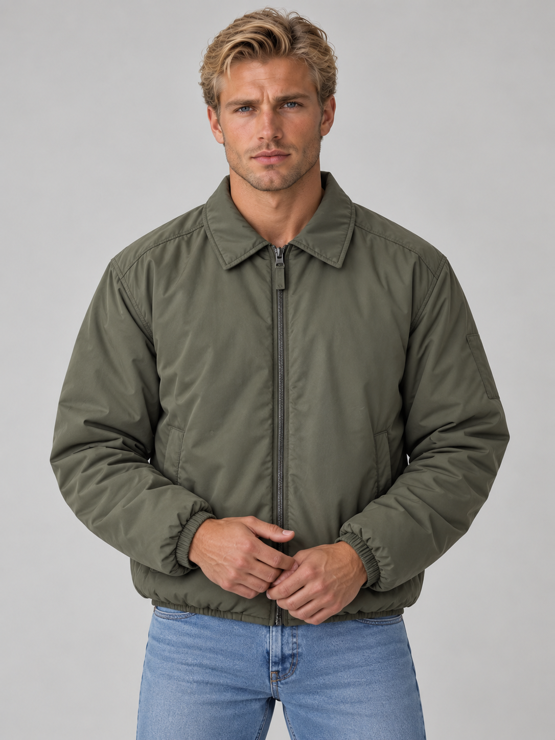 Man wearing olive green lightweight padded bomber jacket with full zip and collar over blue jeans