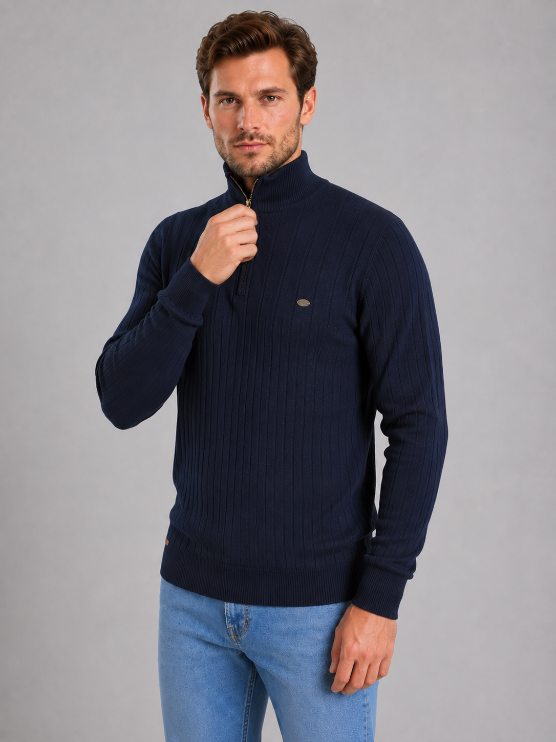 Man wearing navy ribbed funnel neck quarter zip jumper with light blue jeans, hand near zipper