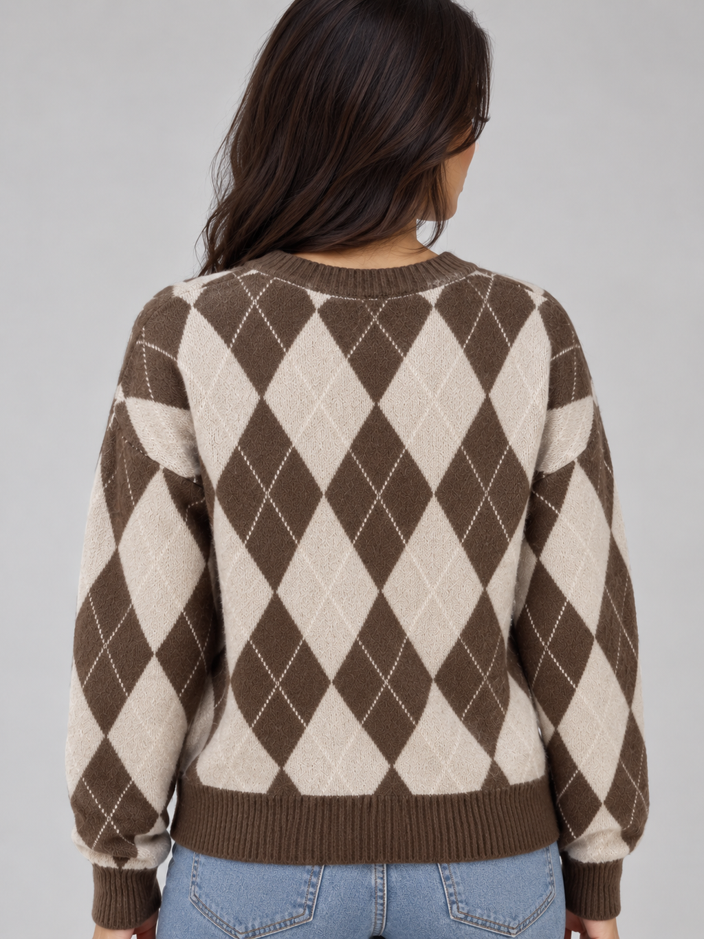 Woman wearing brown and cream argyle knit sweater with crew neck, shown from behind, paired with blue jeans