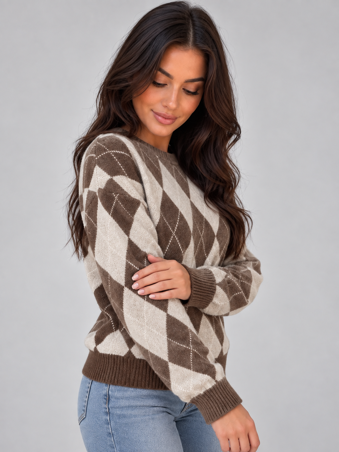 Woman wearing brown and cream argyle knit sweater with crew neck and long sleeves, styled with light blue jeans