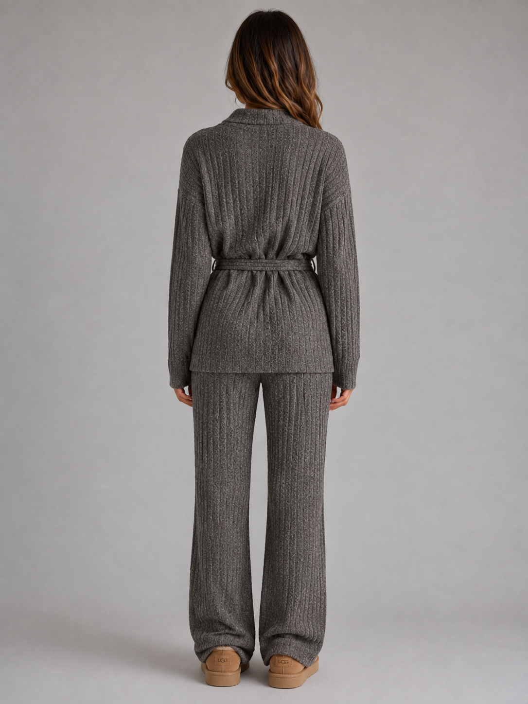 Woman wearing gray ribbed knit roll neck jumper and matching wide leg trousers set, shown from behind
