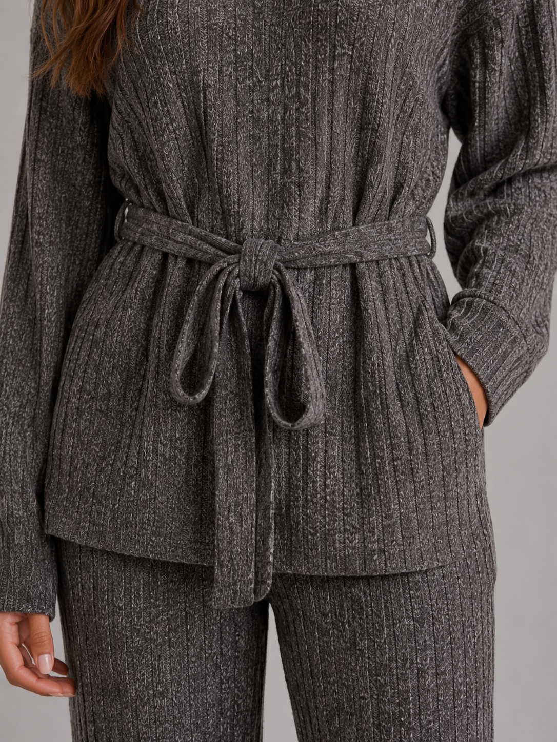 Woman wearing gray ribbed knit roll neck jumper and matching wide leg trousers set with waist tie