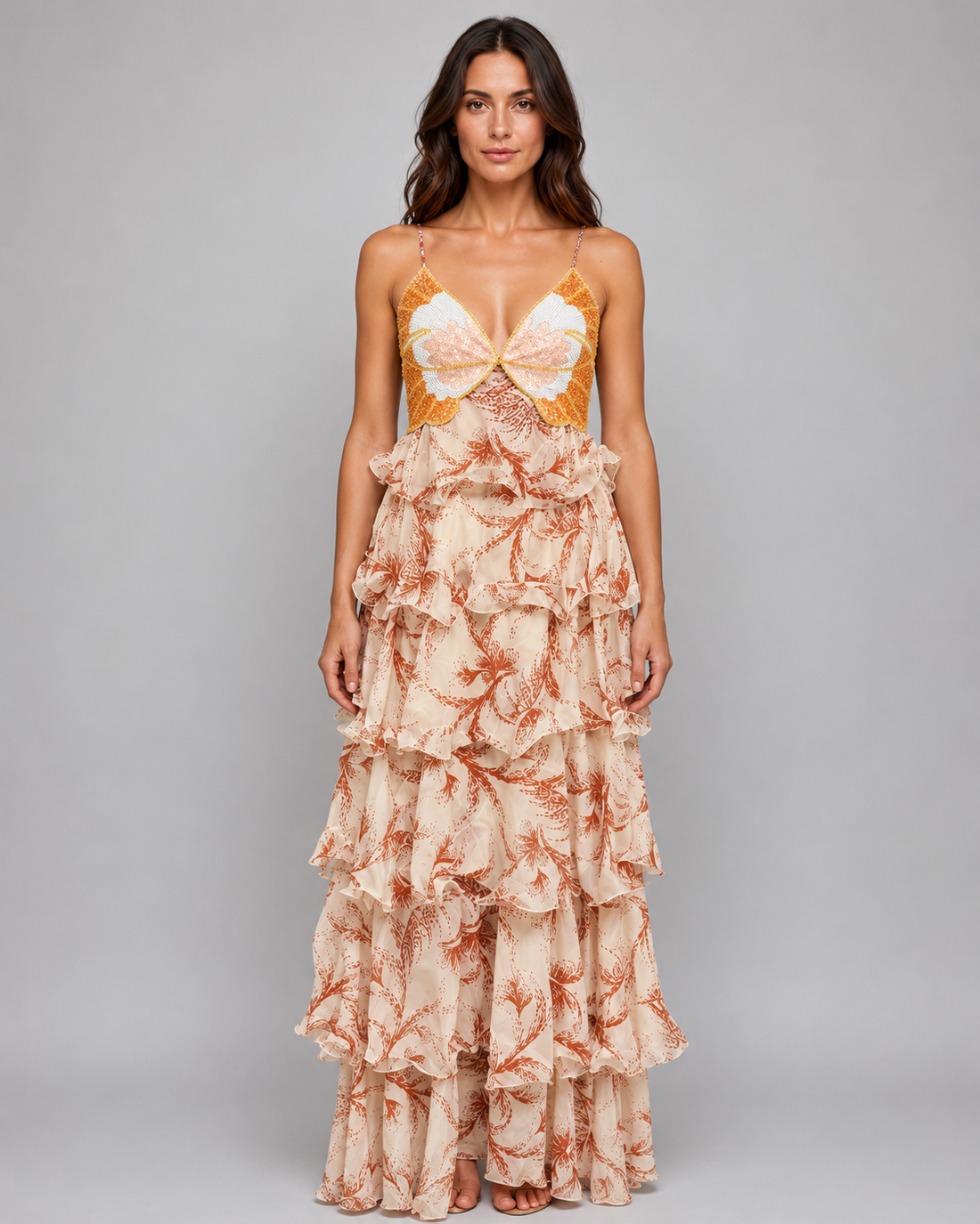 Woman wearing flowing butterfly ruffle maxi dress with coral and white floral print, spaghetti straps, and layered ruffled skirt