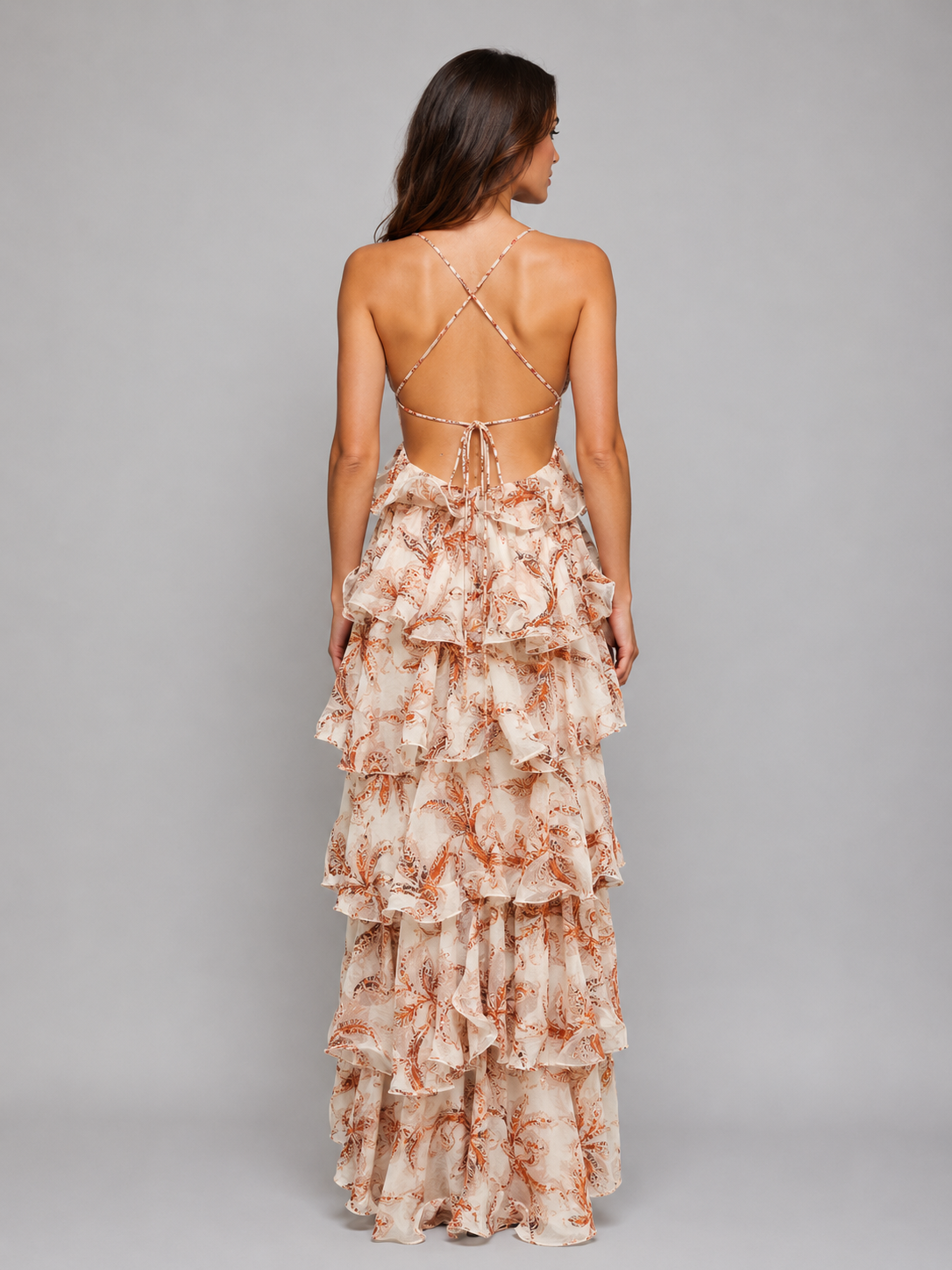 Woman wearing peach butterfly print ruffle maxi dress with open back and tie straps, shown from behind