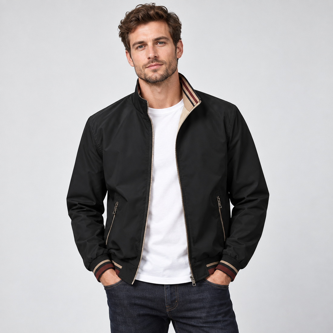 Man wearing black reversible zip-up bomber jacket with tan lining over white t-shirt and dark jeans