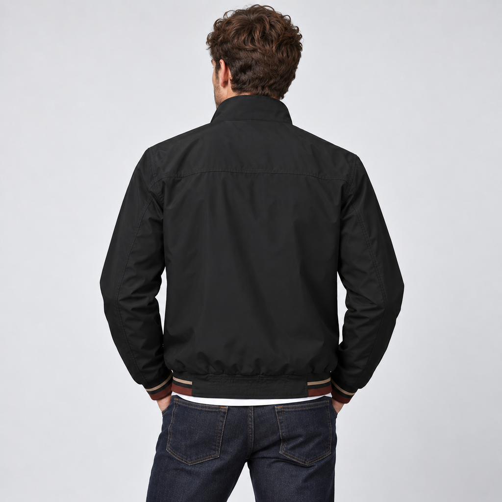 Man wearing black reversible zip-up bomber jacket with striped ribbed cuffs and hem over dark jeans, shown from back