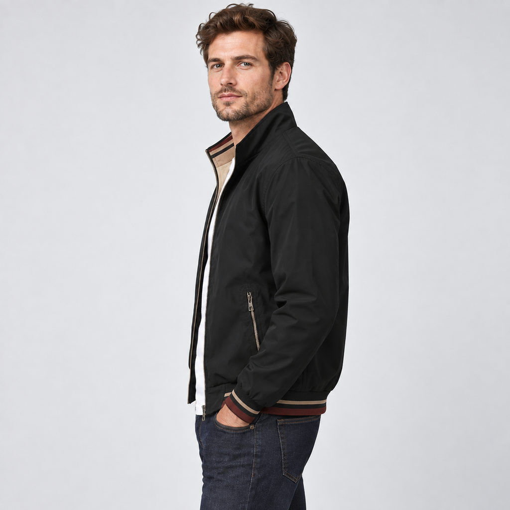 Man wearing black reversible zip-up bomber jacket with beige interior and striped trim, styled with dark jeans