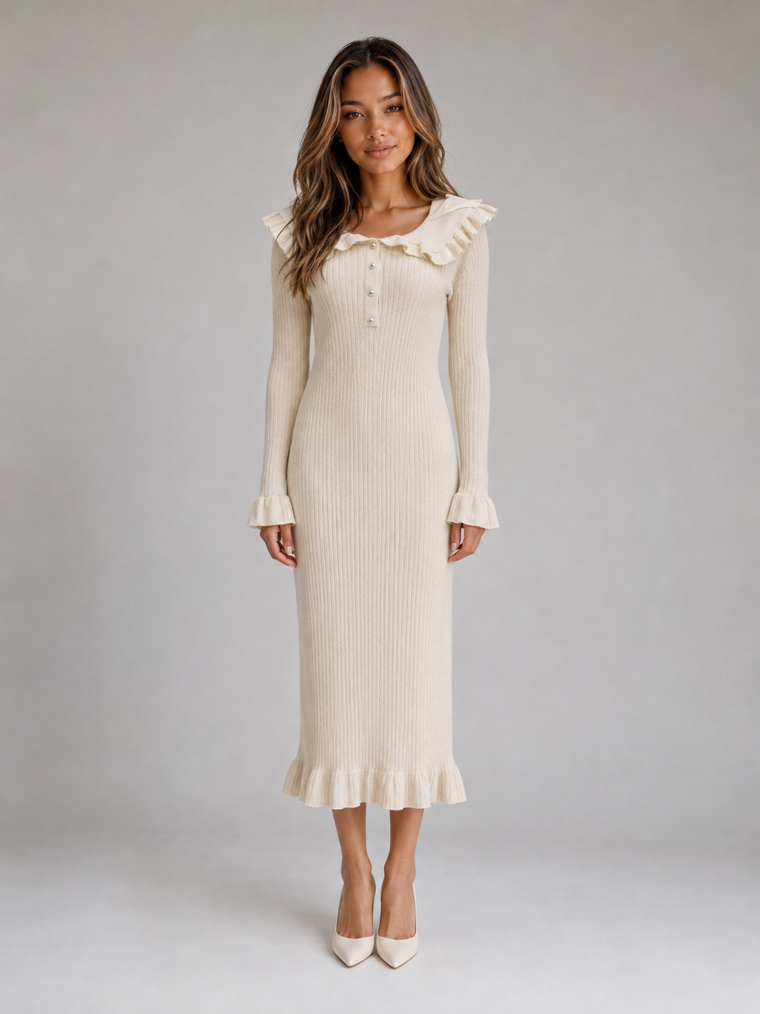 Woman wearing cream long sleeve ribbed knit midi dress with ruffle collar and cuffs, styled with white pointed toe heels