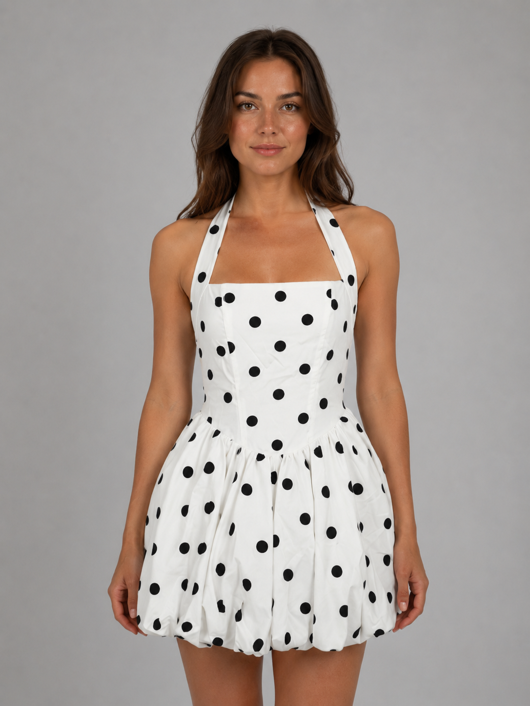 Woman wearing white halter neck mini dress with black polka dots and bubble hem